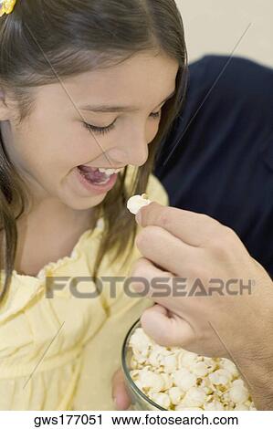 Close-up of a person's hand feeding popcorn to a girl View Large Photo Image Stock Image - Close-up of a person's hand feeding popcorn to a girl. Fotosearch