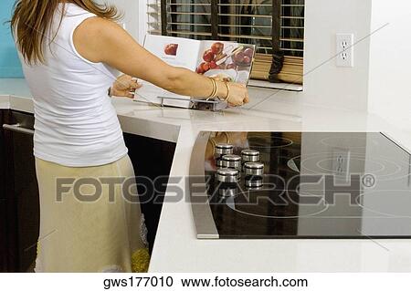 Mature woman reading a cookbook at a kitchen counter View Large Photo Image Stock Image - Mature woman reading a cookbook at a kitchen counter. Fotosearch