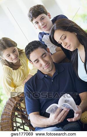 Mid adult man reading a book with his wife and two children View Large Photo Image Stock Photo - Mid adult man reading a book with his wife and two children. Fotosearch