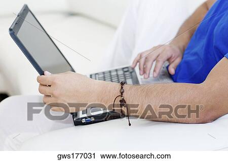 Mid section view of a man using a laptop View Large Photo Image Stock Image - Mid section view of a man using a laptop. Fotosearch