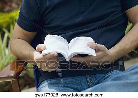 Mid section view of a mid adult man holding a book View Large Photo Image Stock Photo - Mid section view of a mid adult man holding a book. Fotosearch
