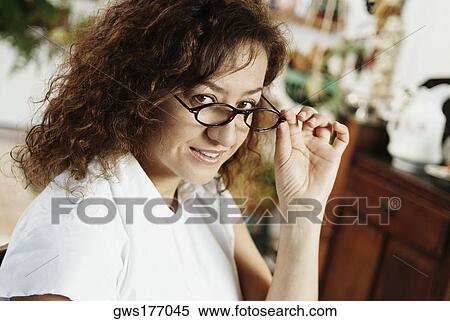 Stock Photography - Portrait of a mature woman peeking over her eyeglasses. Fotosearch