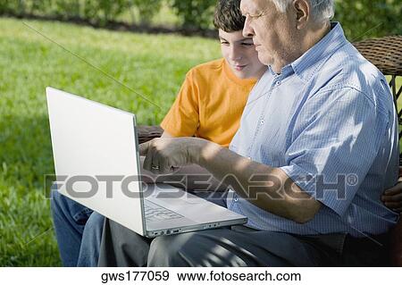Senior man with his grandson using a laptop View Large Photo Image Stock Photo - Senior man with his grandson using a laptop. Fotosearch