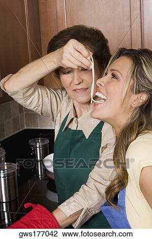 Senior woman feeding noodles to her daughter in the kitchen View Large Photo Image Stock Image - Senior woman feeding noodles to her daughter in the kitchen. Fotosearch
