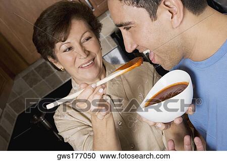 Senior woman feeding tomato soup to her son in the kitchen View Large Photo Image Stock Image - Senior woman feeding tomato soup to her son in the kitchen. Fotosearch