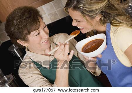 Senior woman feeding tomato soup to her daughter in the kitchen View Large Photo Image Stock Photo - Senior woman feeding tomato soup to her daughter in the kitchen. Fotosearch