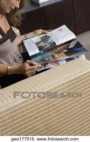 Stock Photography - Side profile of a mature woman sitting in an armchair and reading a magazine. Fotosearch