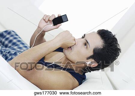 Side profile of a young man listening to an MP3 player View Large Photo Image Stock Image - Side profile of a young man listening to an MP3 player. Fotosearch