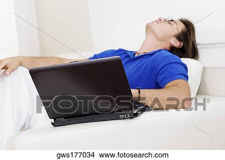 Picture - Side profile of a young man reclining on a couch. Fotosearch