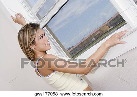 Side profile of a young woman looking through a window and smiling View Large Photo Image Stock Photo - Side profile of a young woman looking through a window and smiling. Fotosearch