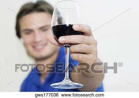 Young man showing a wine glass and smiling View Large Photo Image Stock Photograph - Young man showing a wine glass and smiling. Fotosearch