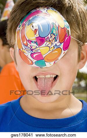 Close-up of a boy sticking her tongue out and covering his eyes with a birthday hat View Large Photo Image Stock Image - Close-up of a boy sticking her tongue out and covering his eyes with a birthday hat. Fotosearch