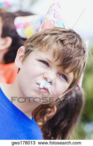 Stock Image - Close-up of a boy with a cake on his mouth. Fotosearch