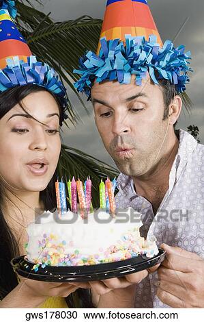 Close-up of a young woman with a mid adult man blowing candles on a birthday cake View Large Photo Image Stock Image - Close-up of a young woman with a mid adult man blowing candles on a birthday cake. Fotosearch
