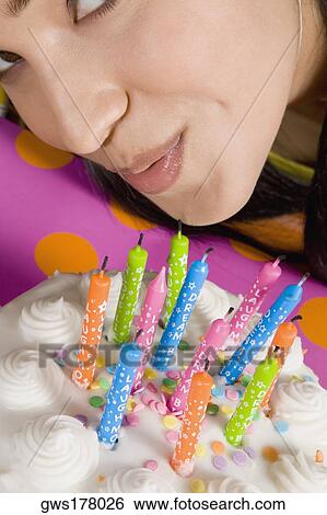High angle view of a young woman blowing candles on a birthday cake View Large Photo Image Stock Photograph - High angle view of a young woman blowing candles on a birthday cake. Fotosearch