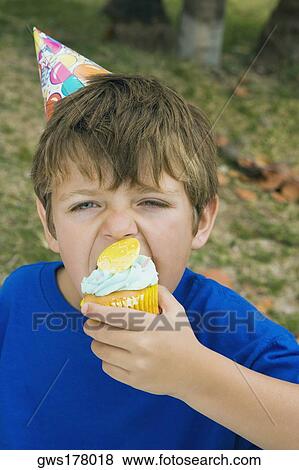 Stock Photo - Portrait of a boy eating a cupcake. Fotosearch