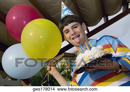 Portrait of a boy holding a birthday cake and balloons View Large Photo Image Picture - Portrait of a boy holding a birthday cake and balloons. Fotosearch