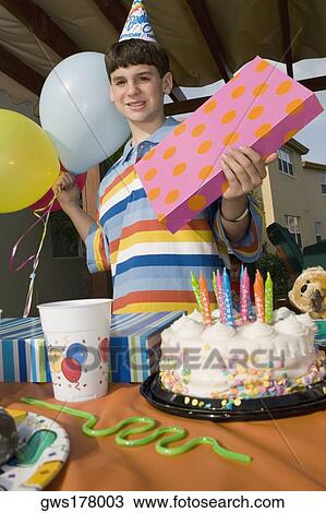 Stock Image - Portrait of a boy holding a birthday present and balloons. Fotosearch