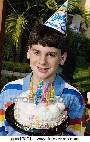 Stock Image - Portrait of a boy holding a birthday cake and smiling. Fotosearch