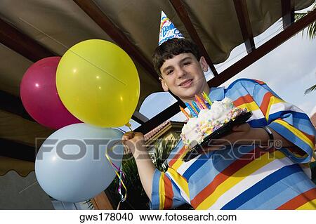 Portrait of a boy holding a birthday cake and balloons View Large Photo Image Stock Image - Portrait of a boy holding a birthday cake and balloons. Fotosearch