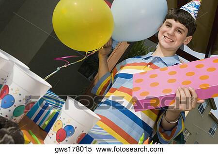 Portrait of a boy holding a birthday present and balloons View Large Photo Image Stock Photography - Portrait of a boy holding a birthday present and balloons. Fotosearch