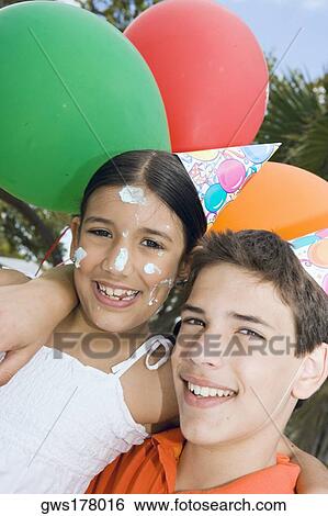 Stock Photograph - Portrait of a boy with his sister wearing birthday hats and smiling. Fotosearch