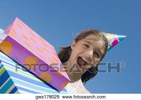 Stock Photo - Portrait of a girl laughing with birthday presents. Fotosearch