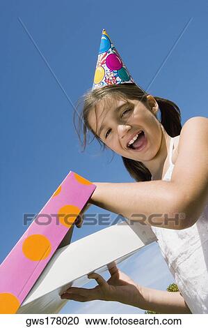 Portrait of a girl opening her birthday present and laughing View Large Photo Image Stock Image - Portrait of a girl opening her birthday present and laughing. Fotosearch