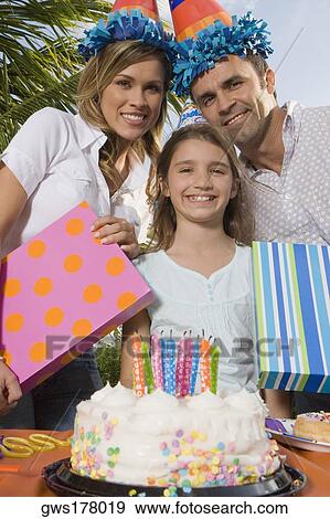 Portrait of a girl smiling with her parents holding birthday presents View Large Photo Image Stock Photo - Portrait of a girl smiling with her parents holding birthday presents. Fotosearch