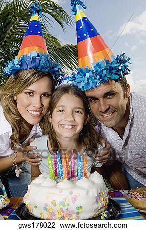 Portrait of a girl with her parents standing in front of a birthday cake and smiling View Large Photo Image Stock Image - Portrait of a girl with her parents standing in front of a birthday cake and smiling. Fotosearch