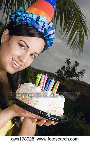 Portrait of a young woman holding a birthday cake and smiling View Large Photo Image Stock Photo - Portrait of a young woman holding a birthday cake and smiling. Fotosearch