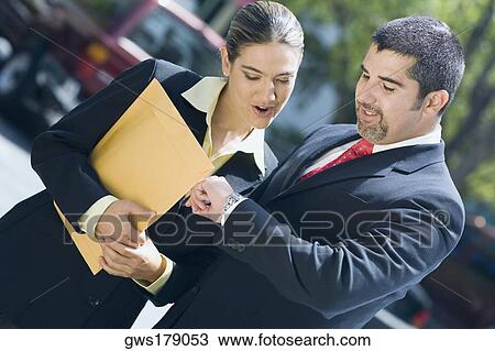 Businessman and a businesswoman checking the time in a wristwatch View Large Photo Image Stock Image - Businessman and a businesswoman checking the time in a wristwatch. Fotosearch