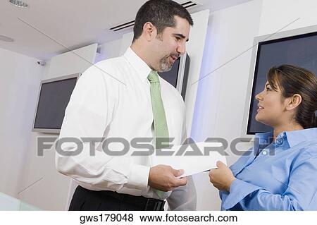 Stock Photo - Businessman giving a document to a businesswoman. Fotosearch