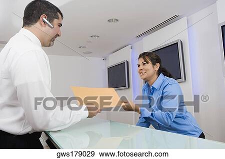 Businessman giving a file to a businesswoman View Large Photo Image Stock Photo - Businessman giving a file to a businesswoman. Fotosearch