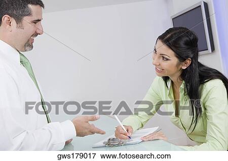 Businesswoman talking to a businessman while writing View Large Photo Image Stock Photo - Businesswoman talking to a businessman while writing. Fotosearch