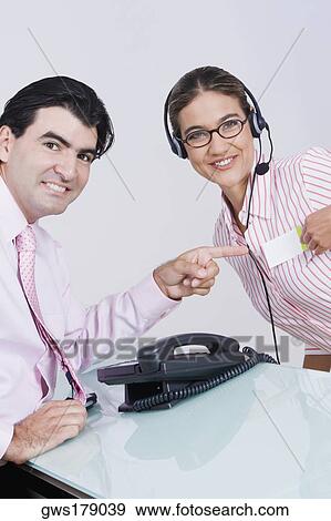 Stock Photo - Portrait of a businessman pointing at the name tag of a businesswoman. Fotosearch