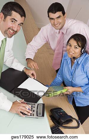 Portrait of a businessman using a calculator with a mid adult man and a young woman smiling View Large Photo Image Stock Photography - Portrait of a businessman using a calculator with a mid adult man and a young woman smiling. Fotosearch