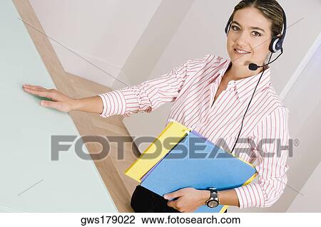 Portrait of a businesswoman wearing a headset and carrying files View Large Photo Image Stock Image - Portrait of a businesswoman wearing a headset and carrying files. Fotosearch