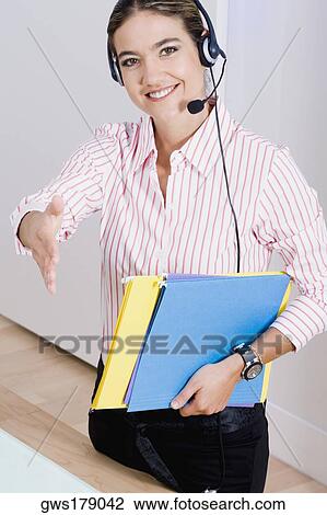 Stock Image - Portrait of a businesswoman wearing a headset and carrying files. Fotosearch