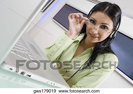 Portrait of a young woman wearing a headset and smiling View Large Photo Image Stock Photo - Portrait of a young woman wearing a headset and smiling. Fotosearch