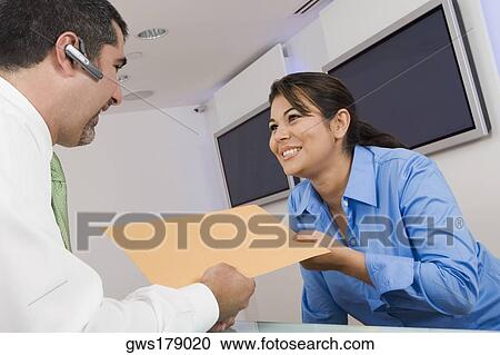 Stock Image - Receptionist giving a file to a businessman. Fotosearch