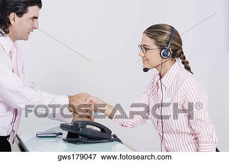 Stock Photo - Side profile of a businessman and a businesswoman shaking hands. Fotosearch