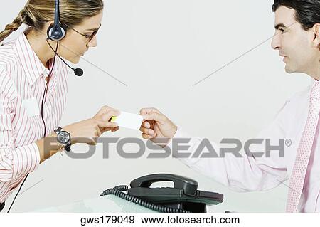 Side profile of a businessman giving a business card to a receptionist View Large Photo Image Stock Photo - Side profile of a businessman giving a business card to a receptionist. Fotosearch
