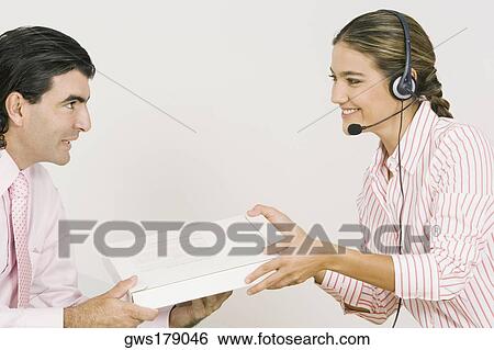 Side profile of a businesswoman giving a package to a businessman View Large Photo Image Stock Photograph - Side profile of a businesswoman giving a package to a businessman. Fotosearch