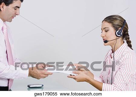 Stock Photography - Side profile of a businesswoman giving a document to a businessman. Fotosearch