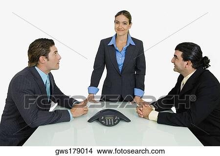 Picture - Side profile of two businessmen and a businesswoman in a conference room. Fotosearch