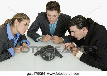 Picture - Three businessmen listening to a conference call. Fotosearch