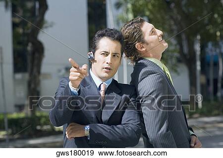 Businessman leaning against another businessman and pointing forward View Large Photo Image Stock Photo - Businessman leaning against another businessman and pointing forward. Fotosearch