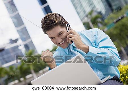 Picture - Businessman talking on a mobile phone and looking excited. Fotosearch