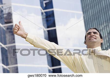 Businessman using a bluetooth device and making a thumbs up sign View Large Photo Image Stock Image - Businessman using a bluetooth device and making a thumbs up sign. Fotosearch